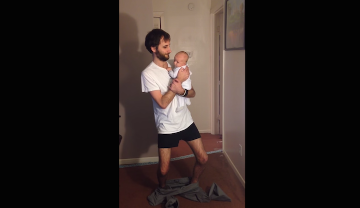 Puttings pants on holding baby