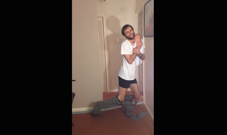 Puttings pants on holding baby