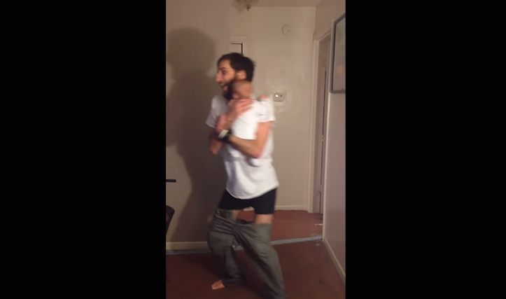 Puttings pants on holding baby